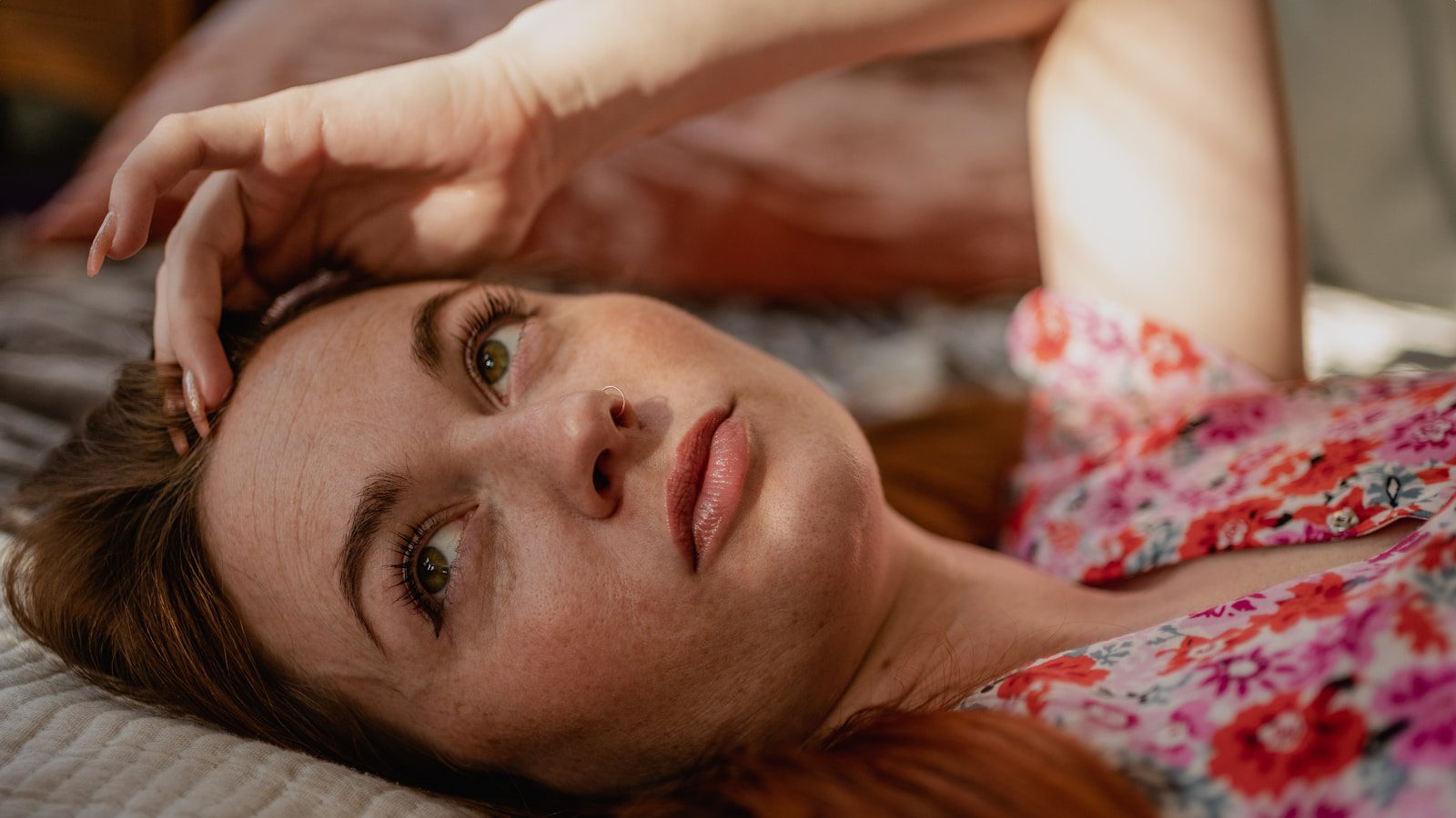 a close up of a woman lying down and looking at the camera