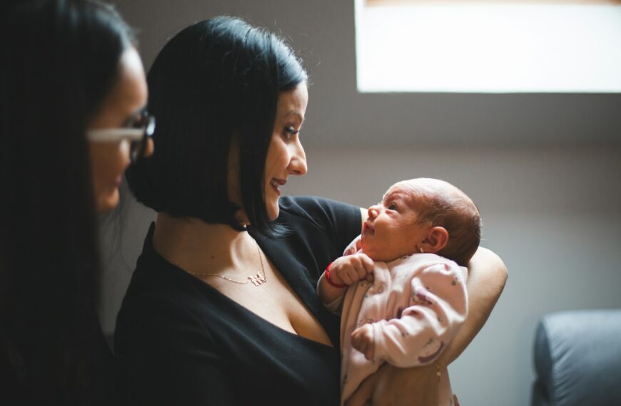 Mother holding her newborn baby with another woman watching