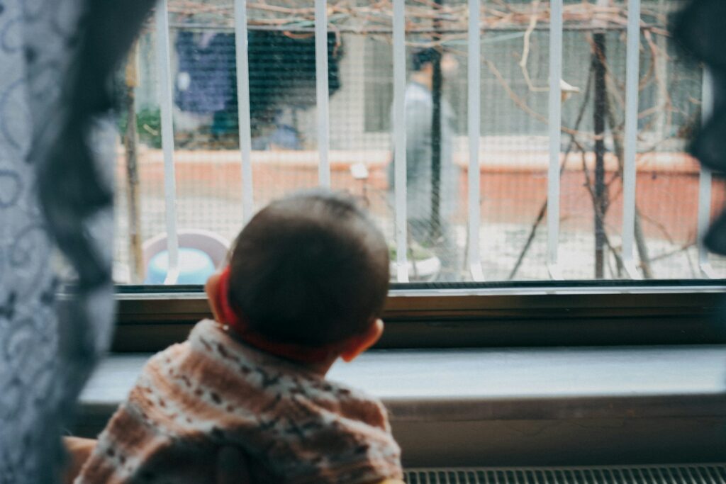 baby in white and red shirt sitting on white window