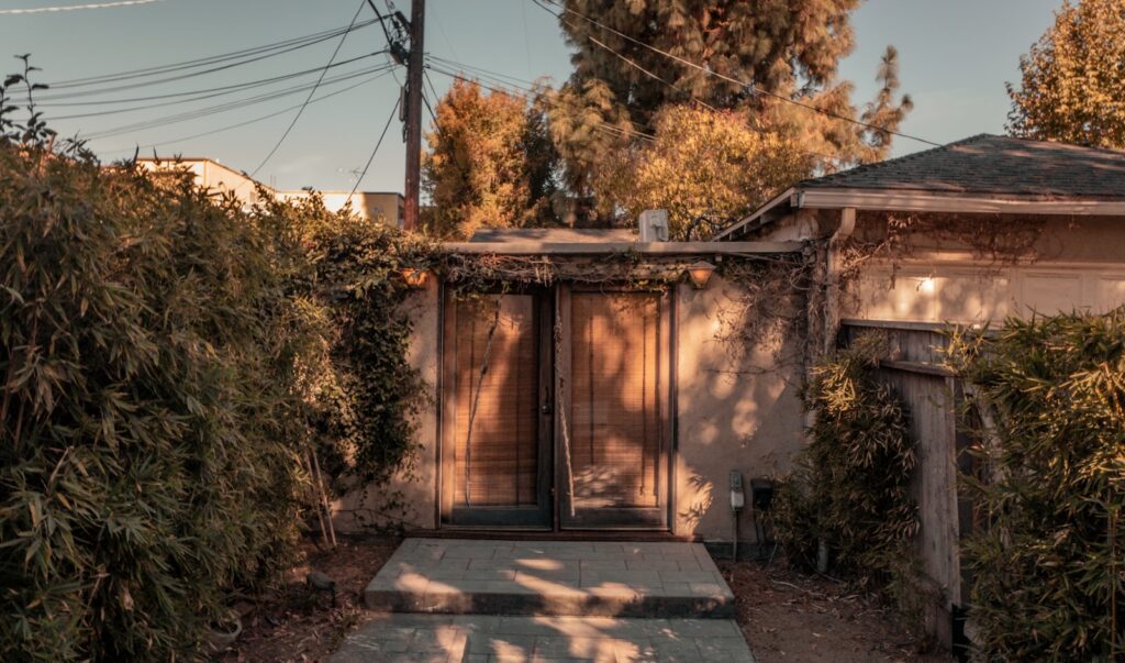 Double doors set into a stucco wall with foliage.