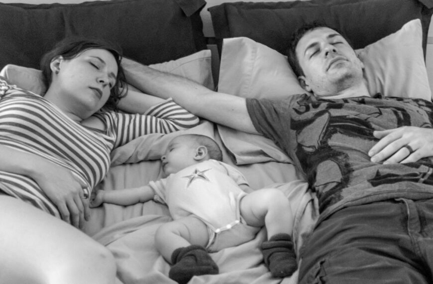 a man and a woman laying in bed with a baby