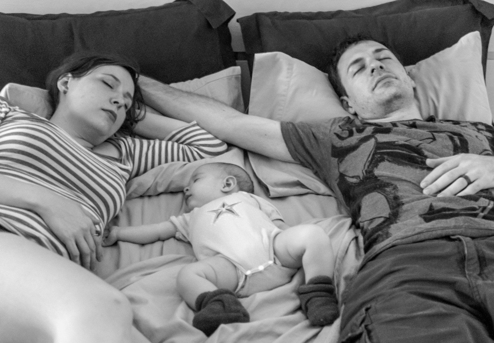 a man and a woman laying in bed with a baby