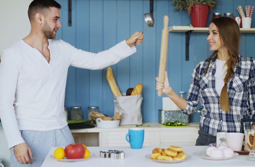Couple playfully fighting with rolling pin in kitchen