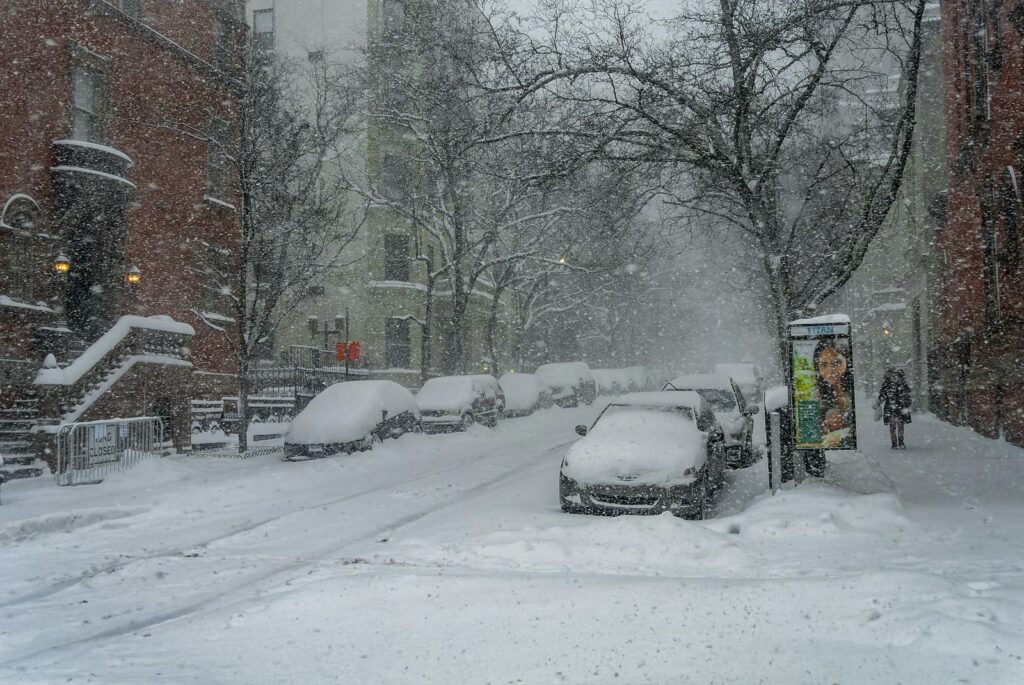a snowy street with cars parked on the side