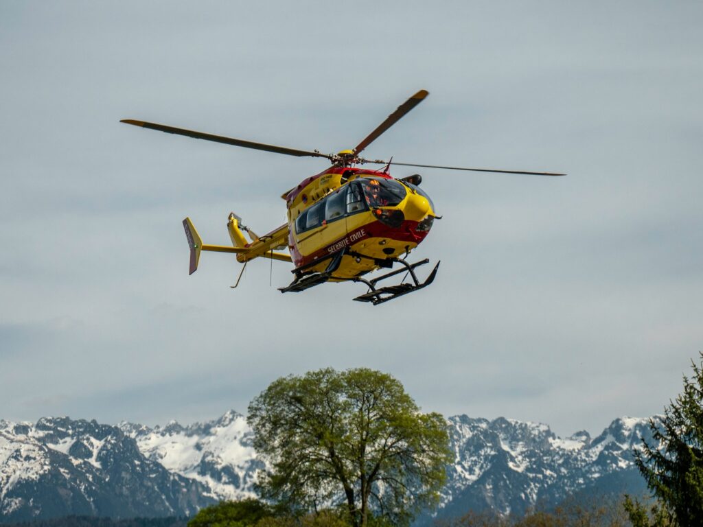 yellow and black helicopter flying over snow covered mountain during daytime