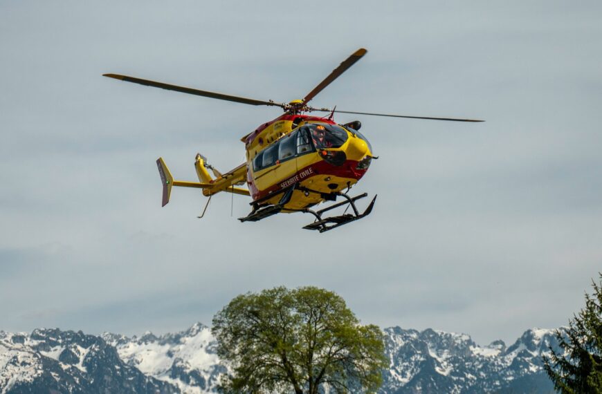 yellow and black helicopter flying over snow covered mountain during daytime