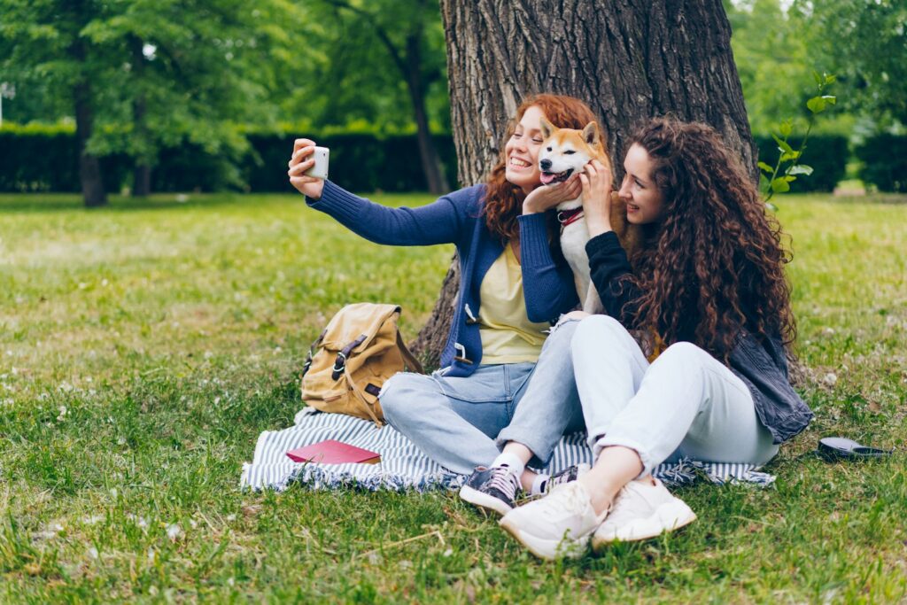 two women sitting in the grass with a dog
