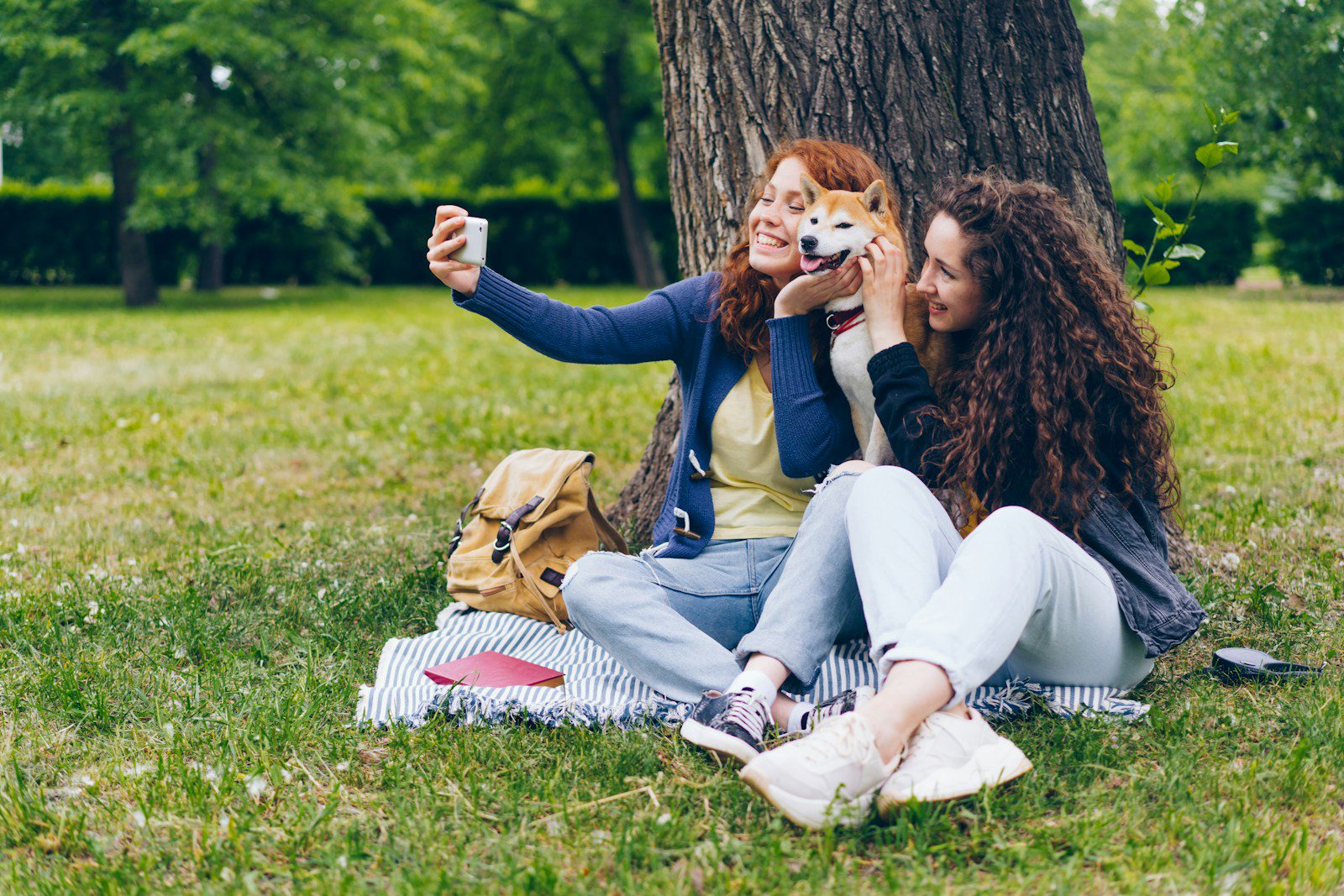 two women sitting in the grass with a dog