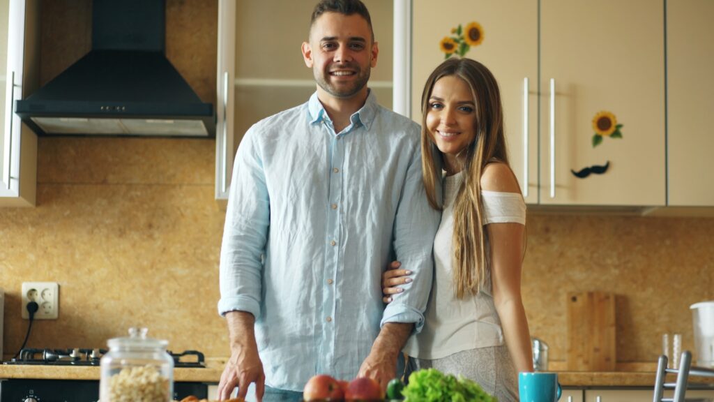 Couple standing in a kitchen with fresh produce.