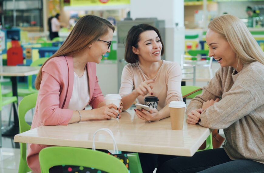 Three women laughing and talking at a table.