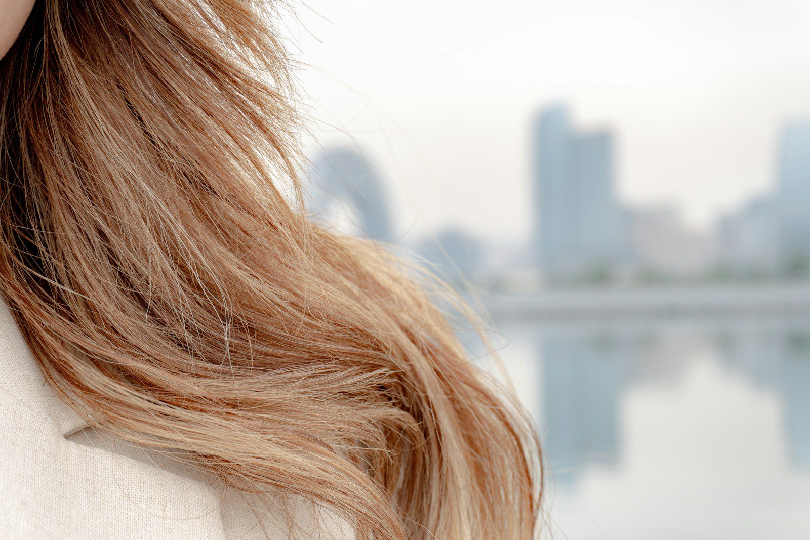 Long hair against a blurred city backdrop.