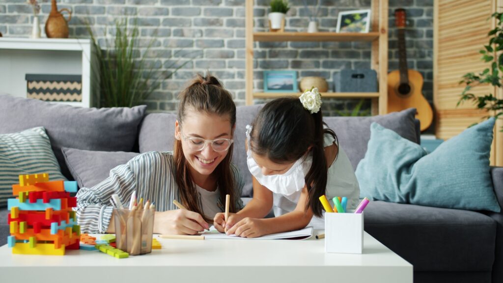Woman and child drawing together on a couch.