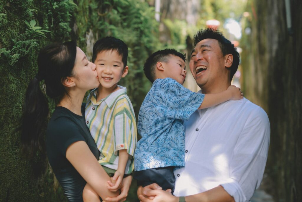 A mother kisses her son while father hugs his son