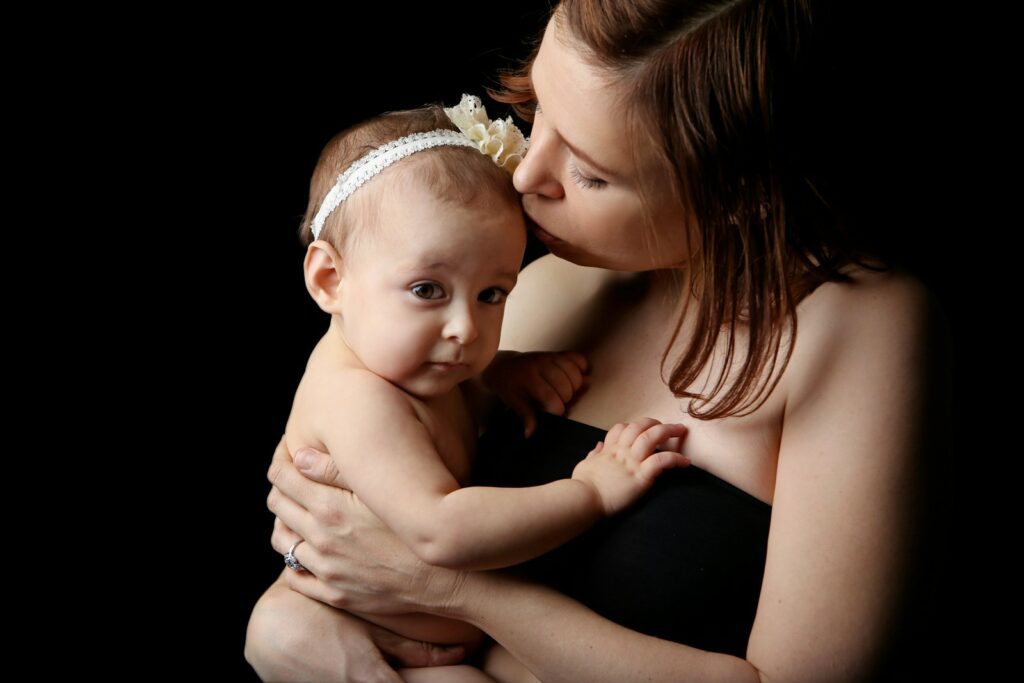 woman kissing baby inside dark room