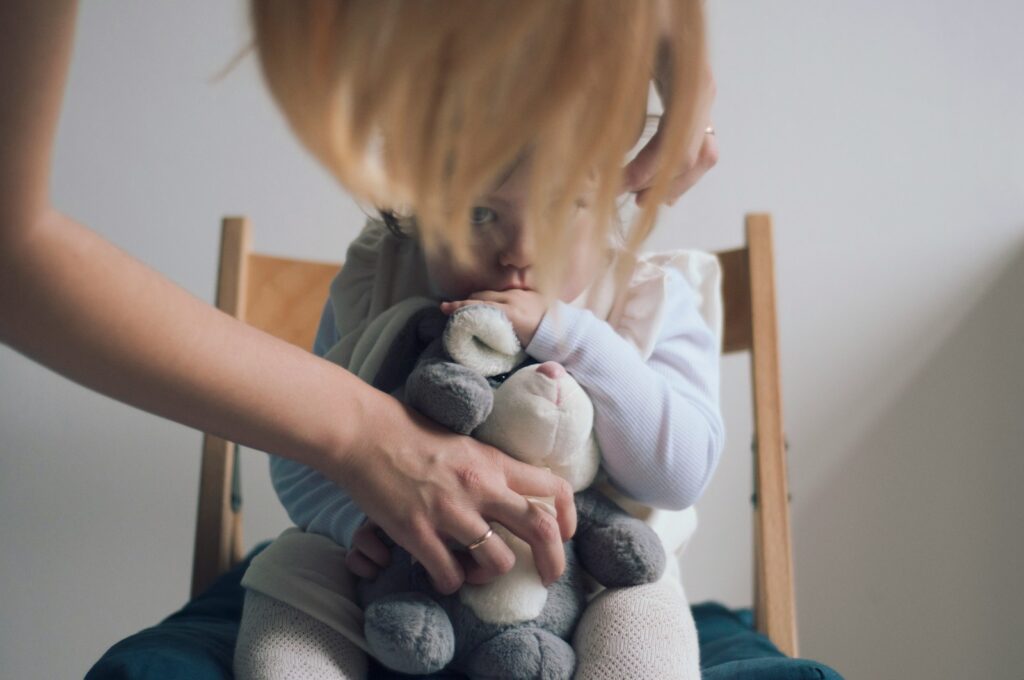 toddler carrying plush toy while sitting