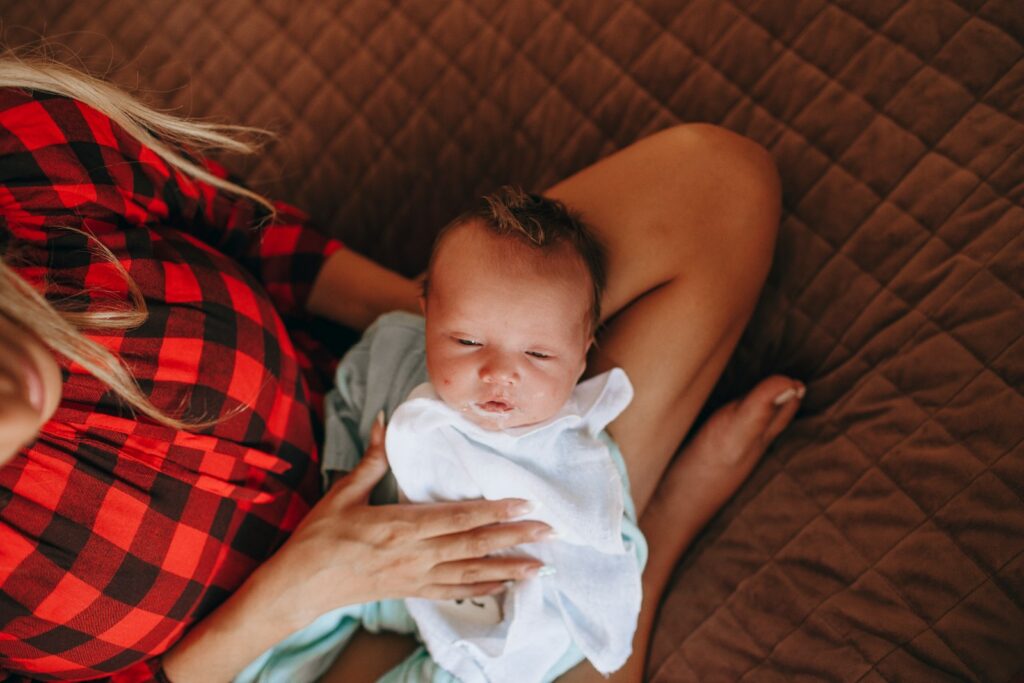 woman in red and black plaid shirt carrying baby in blue onesie