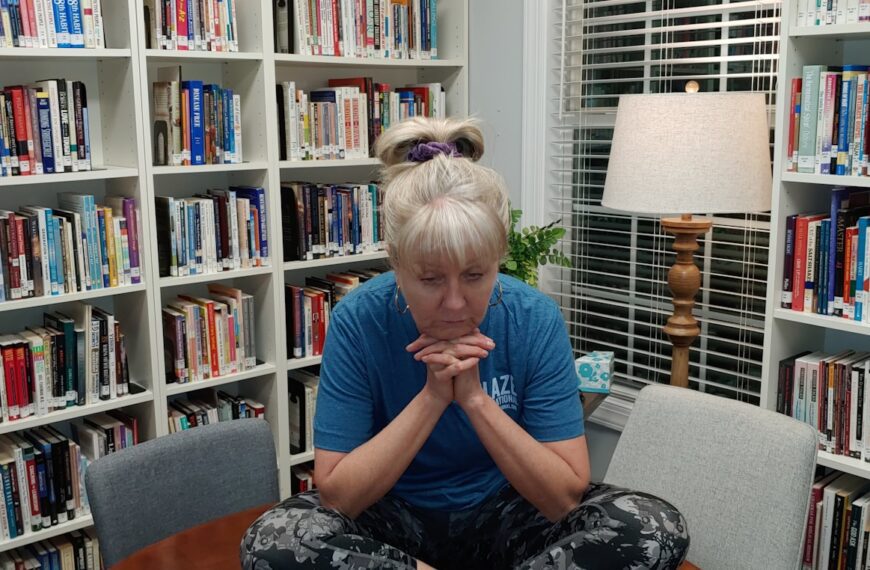 a woman sitting on a table in front of a bookshelf