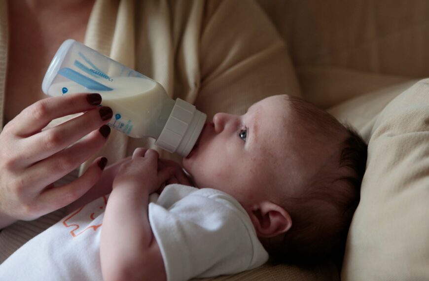 a woman feeding a baby with a bottle of milk