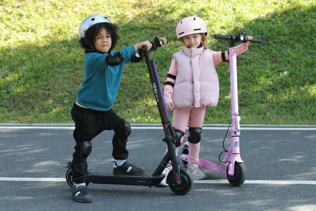 Two children are posing with their scooters.