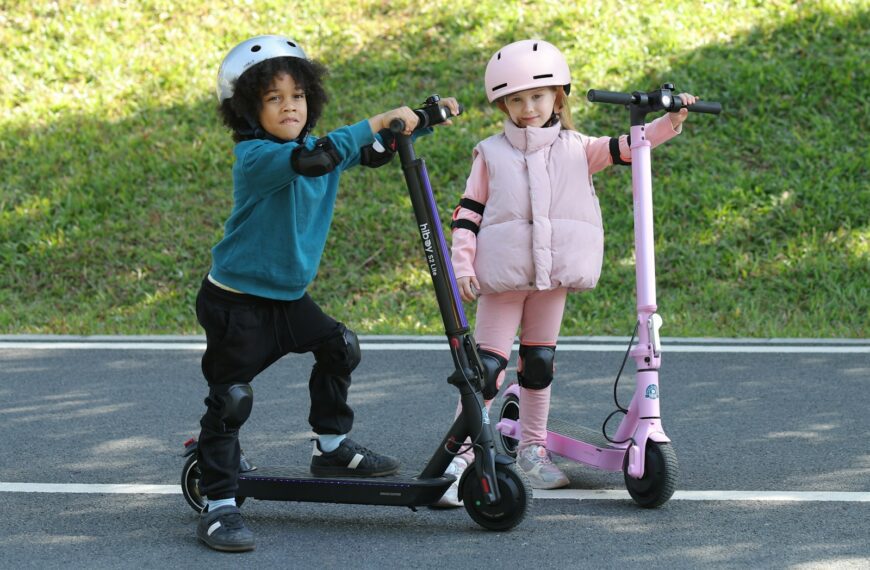 Two children are posing with their scooters.