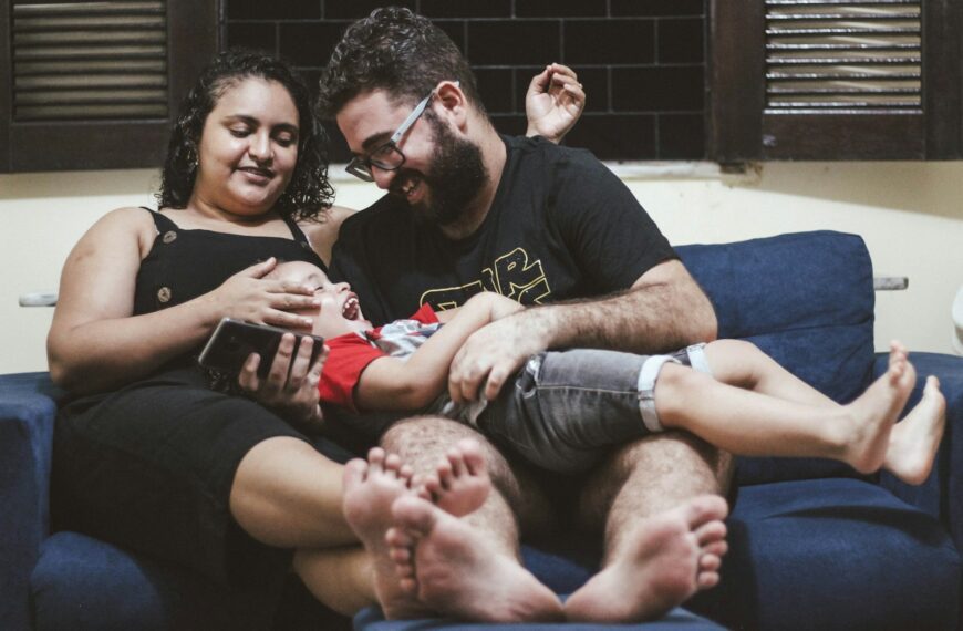 a man and a woman sitting on a couch holding a baby