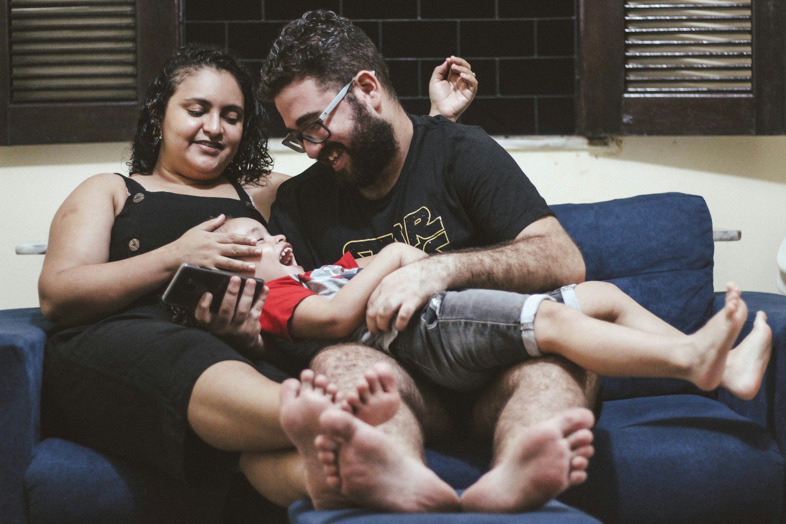 a man and a woman sitting on a couch holding a baby