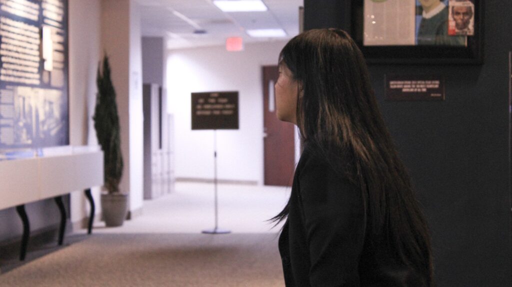 a woman standing in a hallway with a remote in her hand