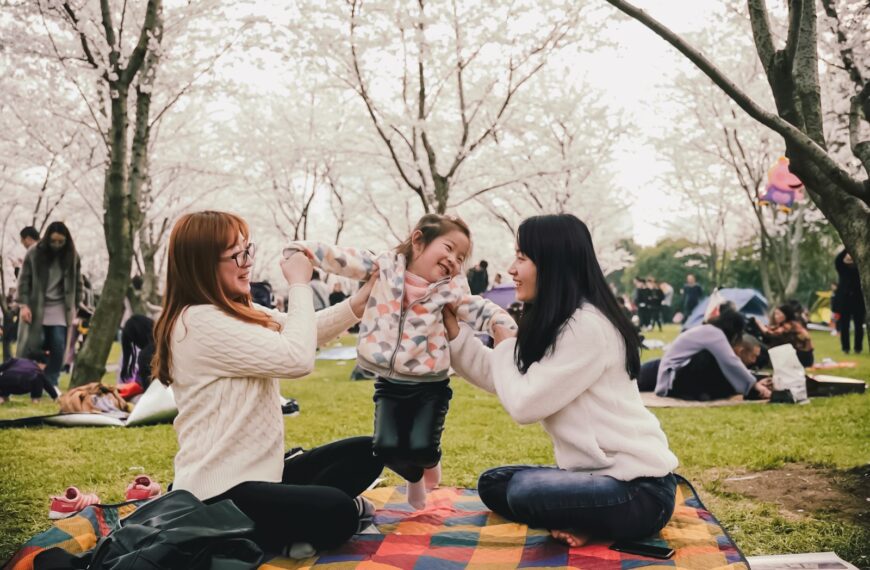a group of women sitting on top of a blanket in a park