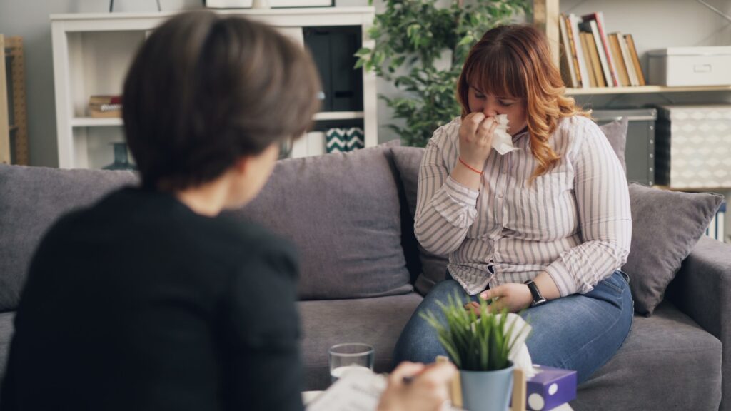 a woman sitting on a couch drinking from a cup