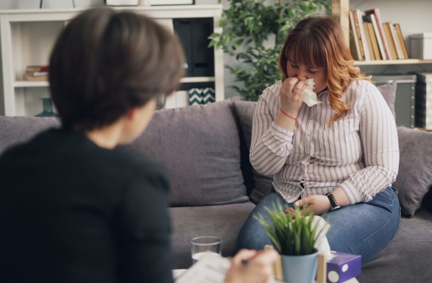 a woman sitting on a couch drinking from a cup