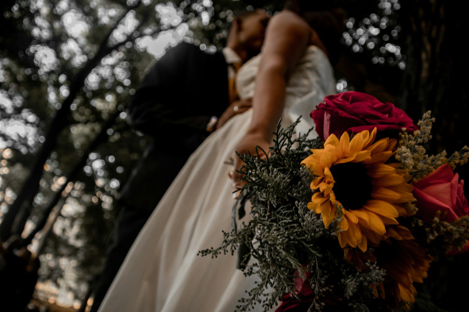 woman in white wedding dress kissing man in black suit