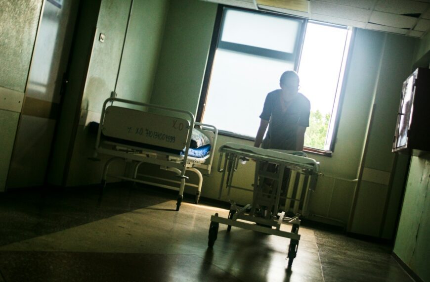 Person sitting by a window in an empty hospital room