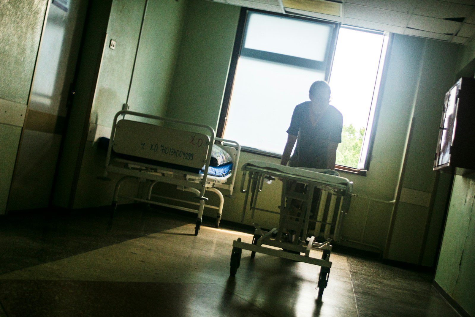 Person sitting by a window in an empty hospital room