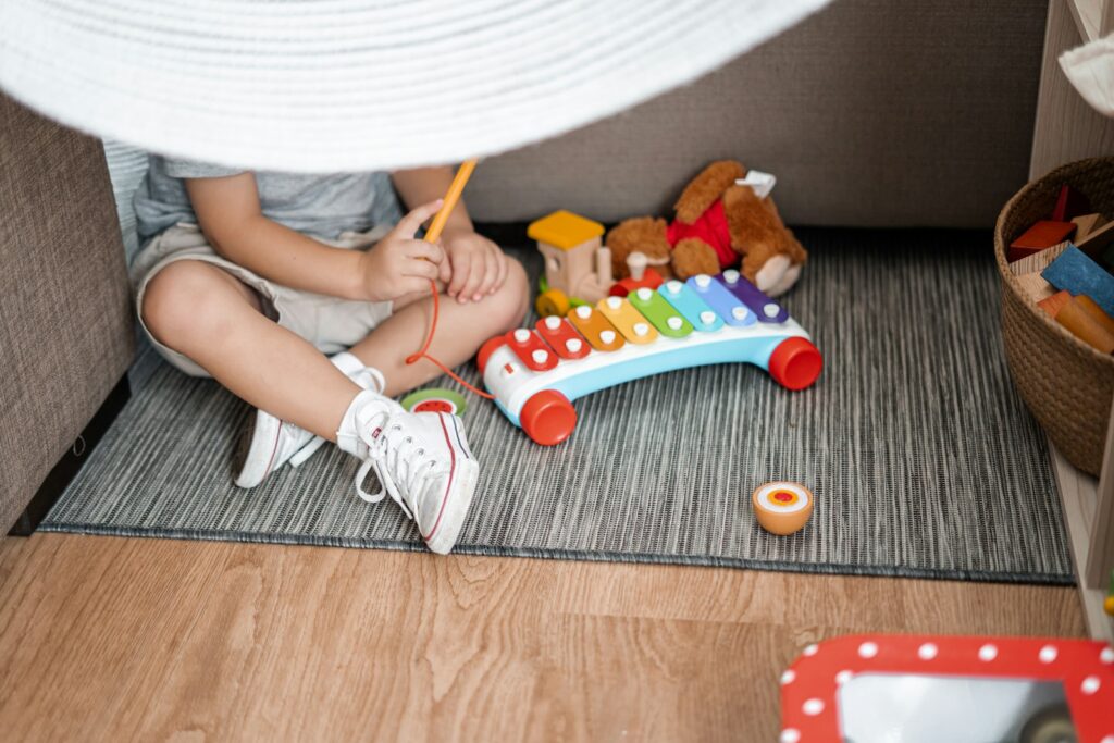 child sitting on floor and playing with xylophone toy