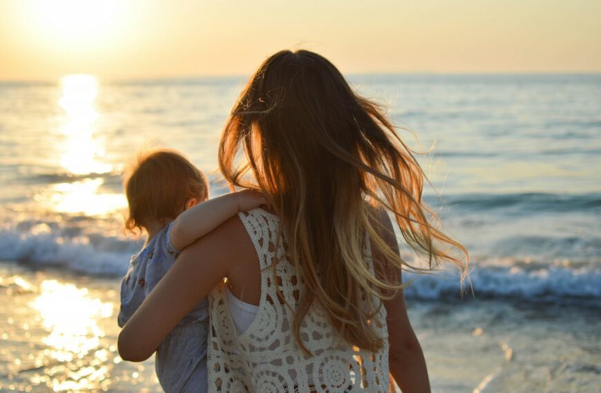 woman in white tank top carrying child in blue shirt