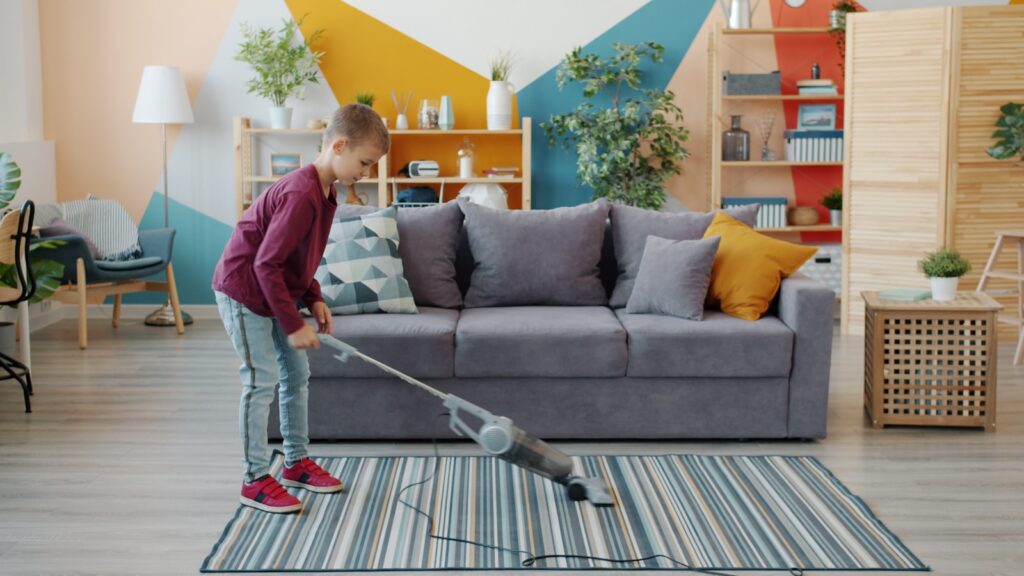 Young girl vacuuming a striped rug in a living room.