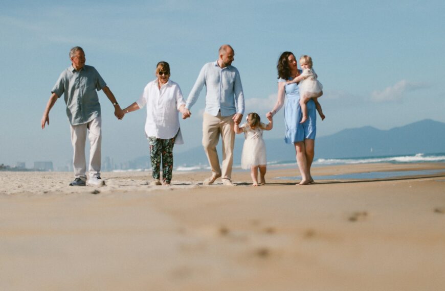 A multi-generational family walks on a sandy beach.