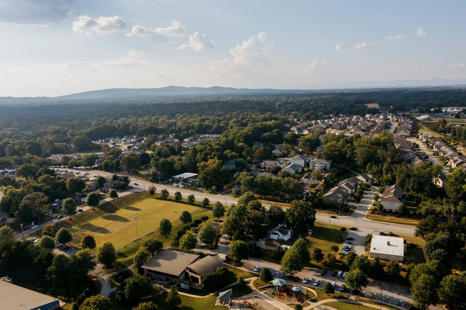 Aerial view of suburban neighborhood with trees and mountains.
