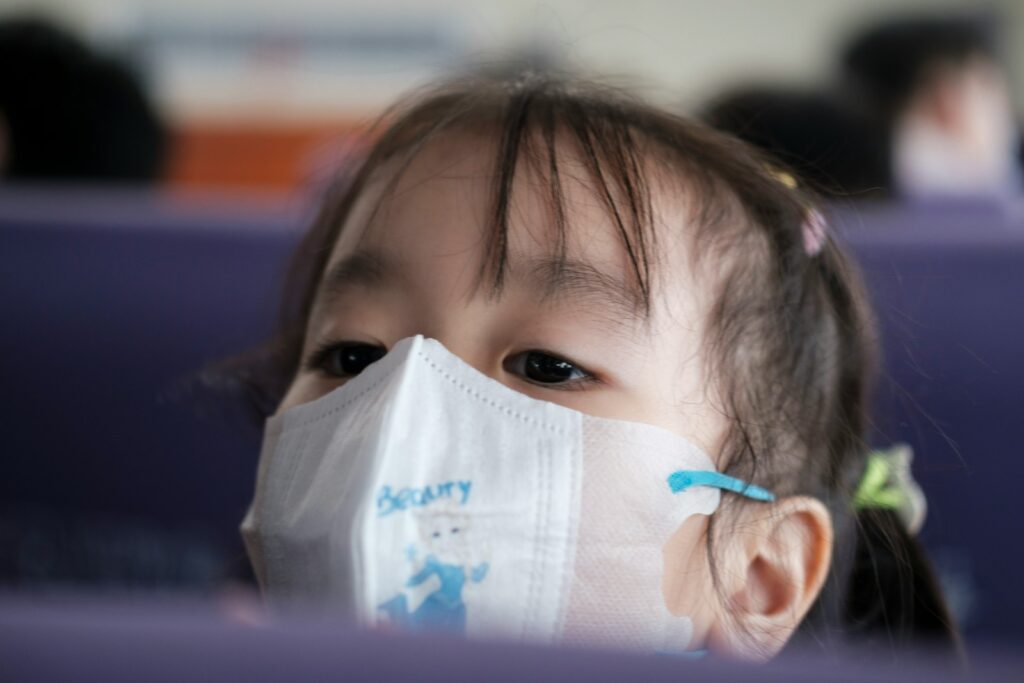 a little girl wearing a face mask on a plane