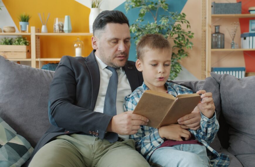 Father and son reading a book together on couch