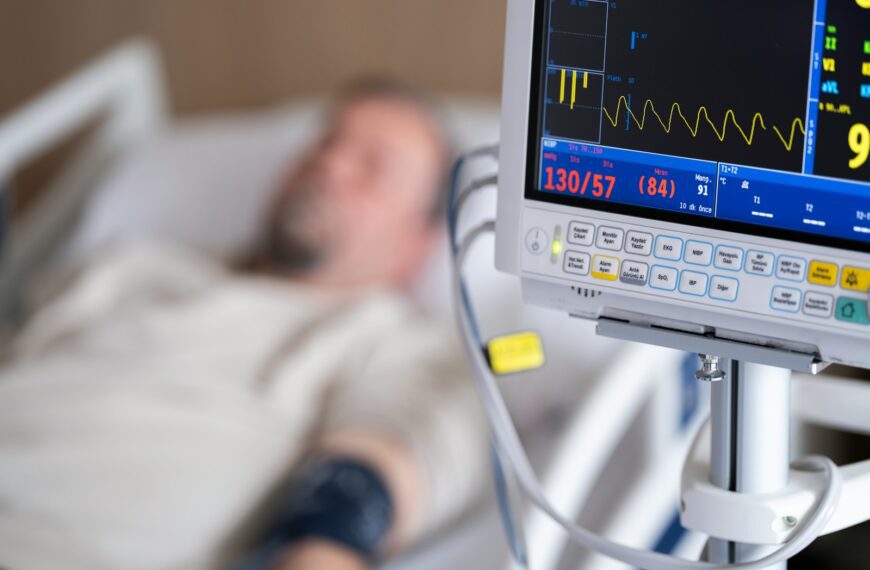 a man laying in a hospital bed next to a monitor