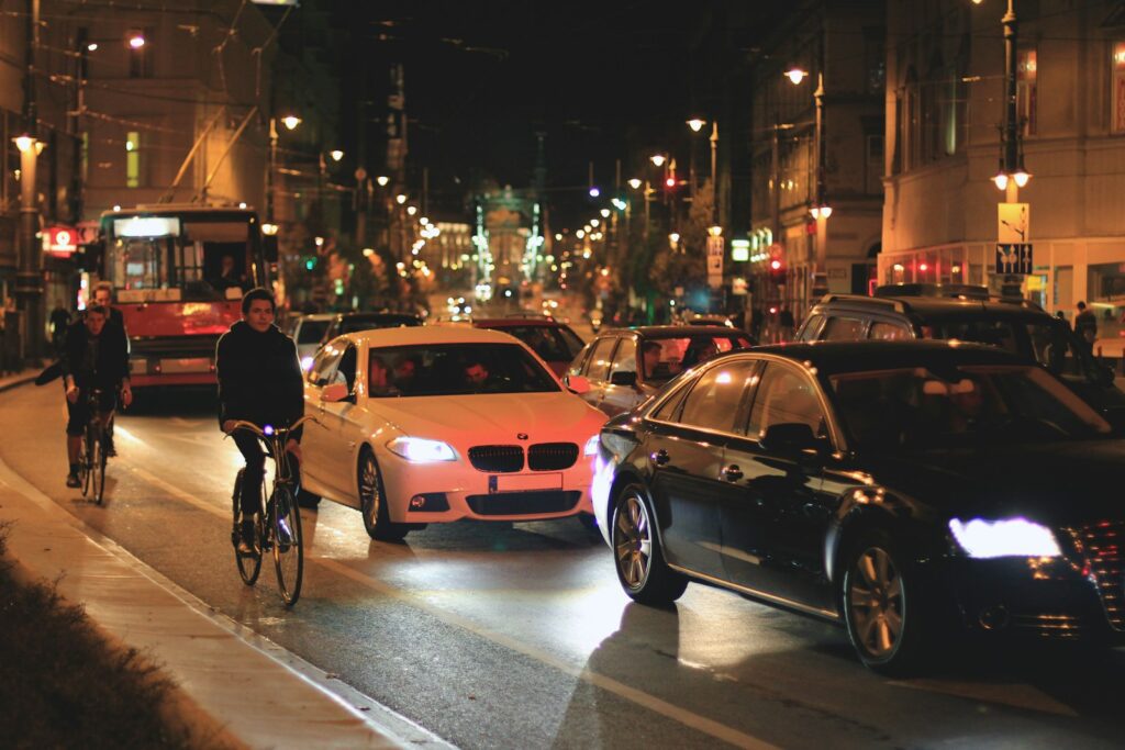 Cars and cyclists navigate a city street at night.