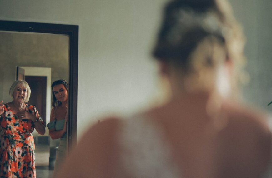 Two women look in mirror at bride getting ready
