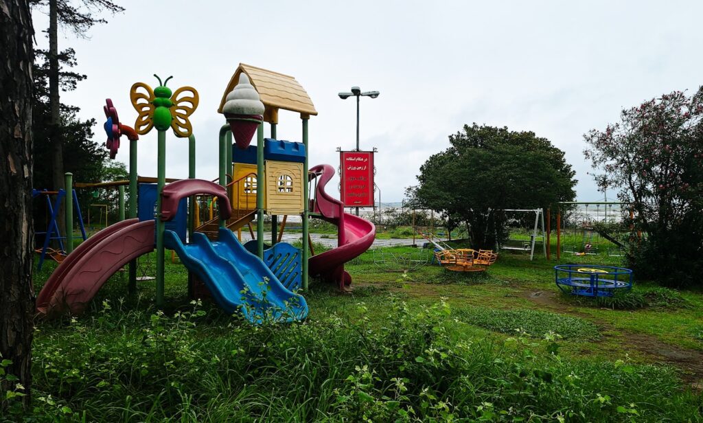 Colorful playground equipment in a grassy park setting.