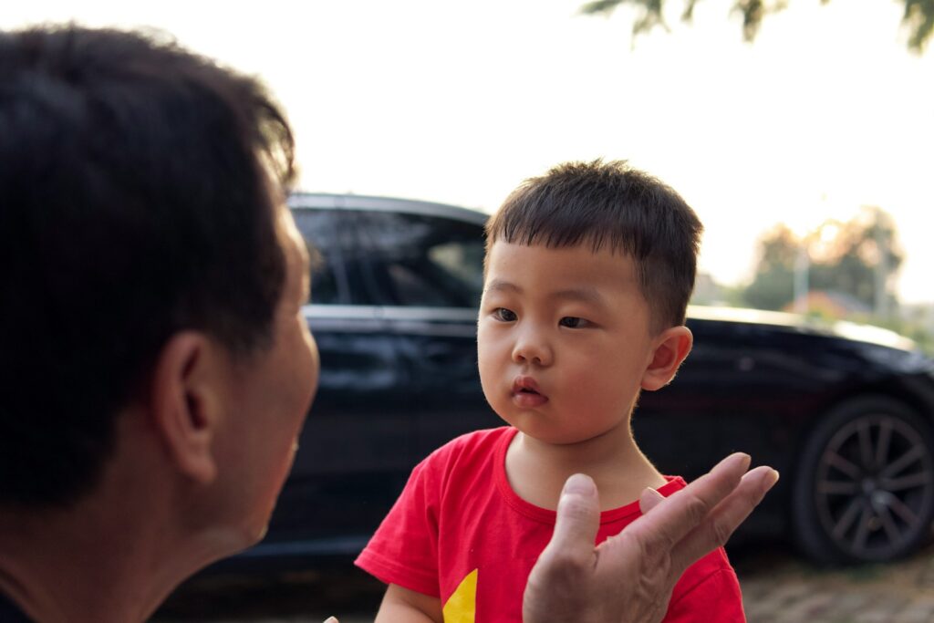 a man talking to a little boy in front of a car