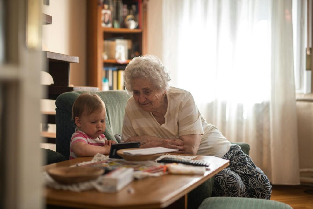 Elderly woman and baby enjoying together time indoors.