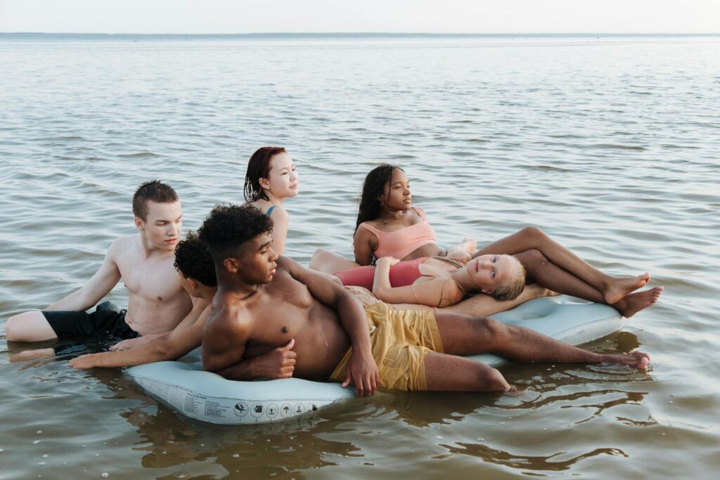 A diverse group of teenagers relaxing on a float in the sea, enjoying a summer vacation.