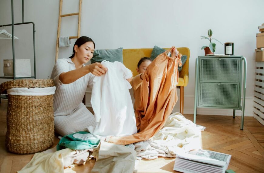 A mother and daughter sort through clothes in a sunlit living room, creating a cozy family moment.