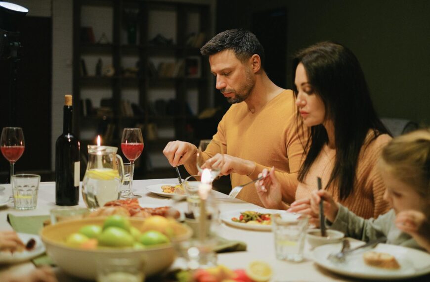 A family gathered around a dinner table indoors, enjoying a meal together with wine and candles.