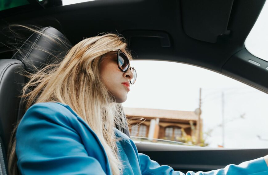 Elegant woman wearing sunglasses is driving through Curitiba, showcasing a modern and stylish look.
